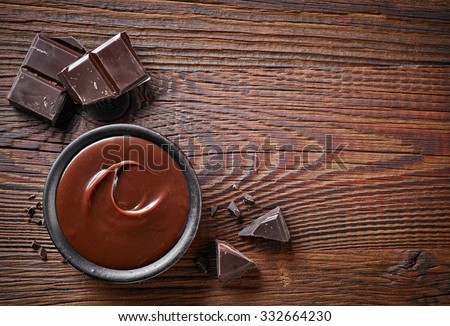 Chocolate cream and chocolate pieces on wooden table, top view