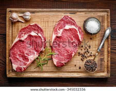 fresh raw beef steak on wooden cutting board, top view