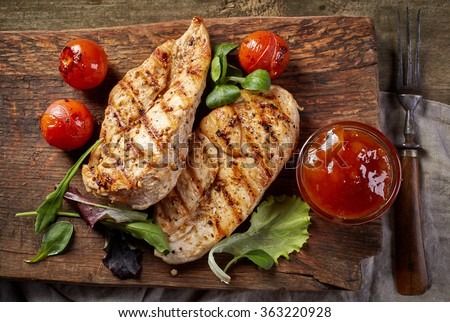 grilled chicken fillets on wooden cutting board