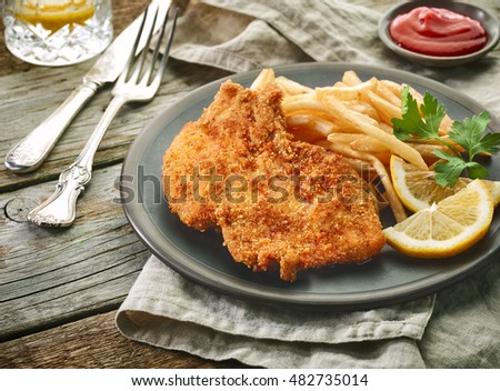pork schnitzel and fried potatoes on wooden table