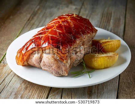 roasted pork on white plate on rustic wooden kitchen table