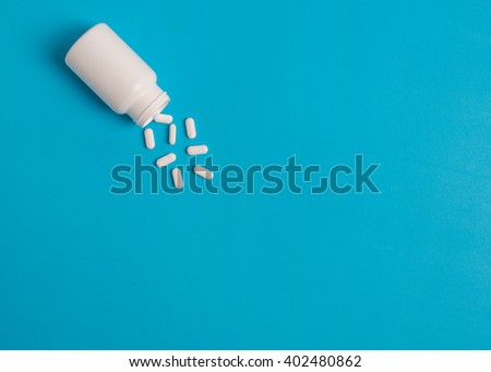 white pills and pill bottle on blue sky background.