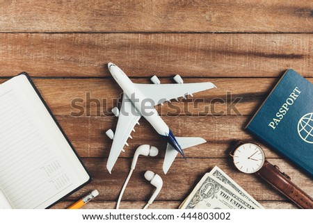 Preparation for Traveling concept, pencil, watch, money, passport, airplane, noted book,  earphone, on a vintage wooden background with copy space.