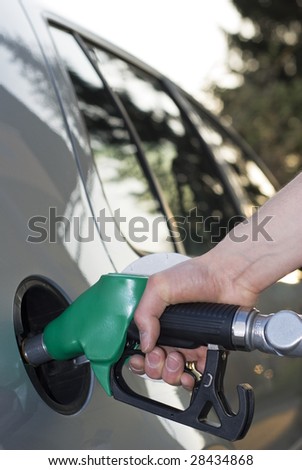 Hand of a man pumping gas in silver car