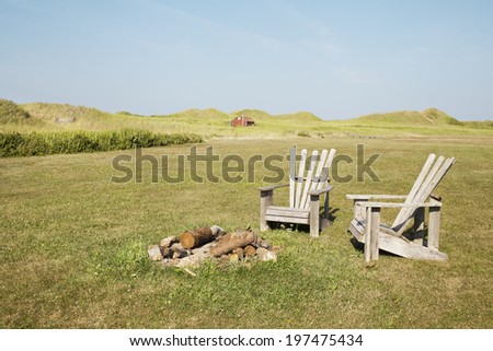 Summer Lounge Chairs -  A set of wooden lounge chairs set around a fire pit, outside a beach cottage in Kensington, Prince Edward Island.