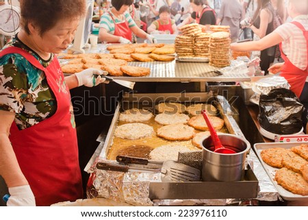 Seoul, South Korea - August 28, 2014: An Asian woman prepares Jeon, a typical korean pancake, at the Gwangjang Market during lunch time.