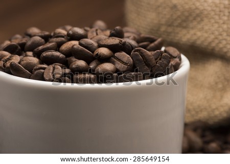 Coffee Beans In Coffee Cup With Coffee Bean Bag in Background