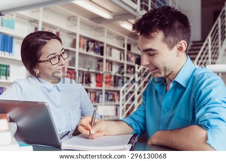 Young students man and woman doing homework and looking at the laptop in the library