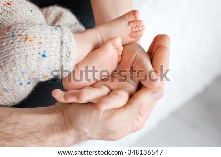 Baby feet in father hands. Tiny Newborn Baby\'s feet on male shaped hands closeup. Dad and his Child. Happy Family concept.
