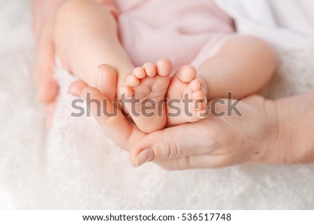 Baby feet in mother hands. Tiny Newborn Baby\'s feet on female Shaped hands closeup. Mom and her Child. Happy Family concept. Beautiful conceptual image of Maternity