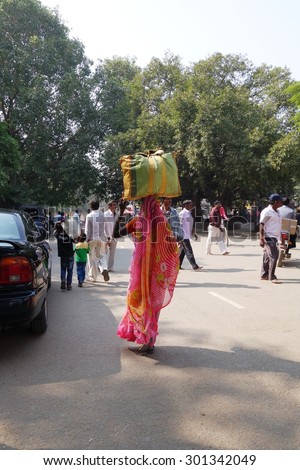 BODH GAYA, BIHAR, INDIA - NOVEMBER 23, 2013: Unidentified Indian woman carries a big bag on her head in Bodh Gaya, India.  Carrying on the head is a common practice in India.