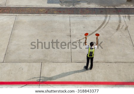 Airport marshalling signal from marshaller for aircraft controls.\
\
Ground Crew Signals\
\
Airport Ground Crew Outfit and Signals\
\
A ground crew  signals the pilot