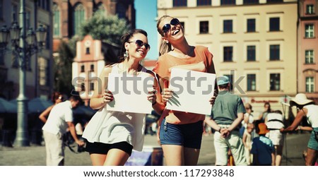 Two smiling friends showing white boards