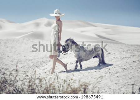 Woman with a white horse on a desert