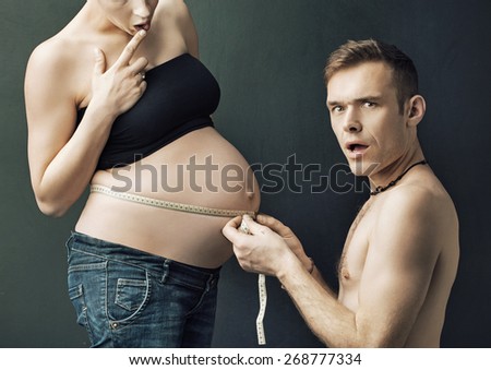 Happy parents measuring on pregnant woman\'s belly