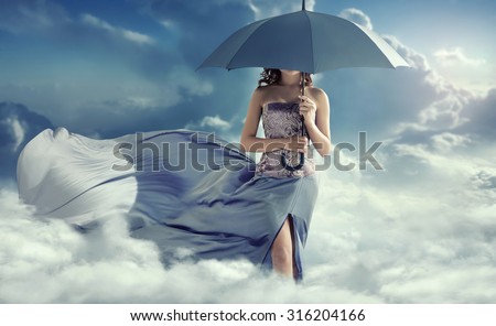 Young lady with an umbrella walking in the clouds