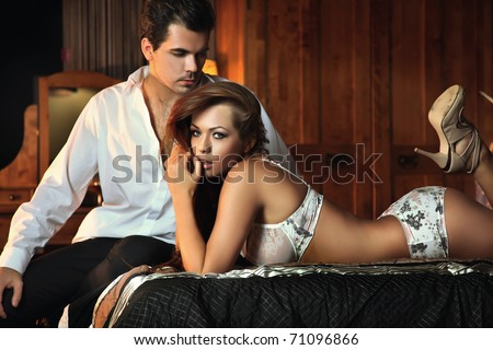 Sensual woman in sexy lingerie sitting on a bed - stock photo
