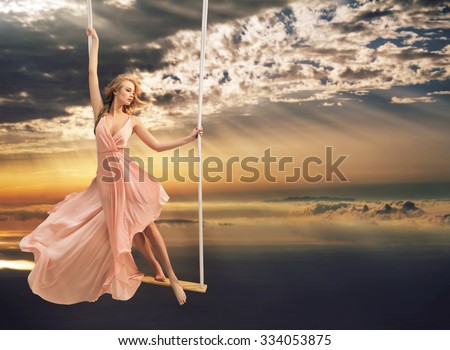 Attractive young lady on a swing above the city