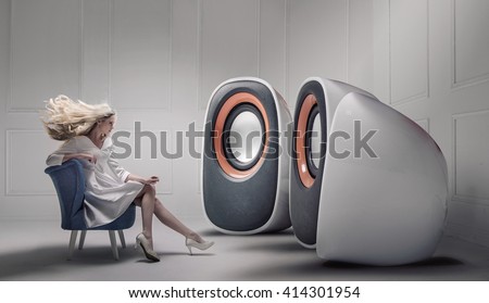 Young fashionable lady listening to big loudspeakers