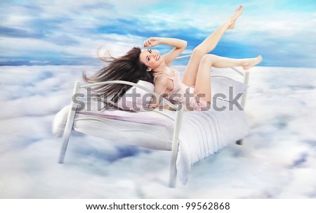Brunette beauty lying on a bed in clouds