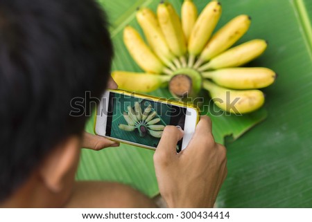 People take pictures with their mobile phones bananas.