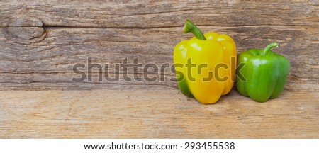 Two colorful fresh green, yellow sweet pepper isolate on the wood background