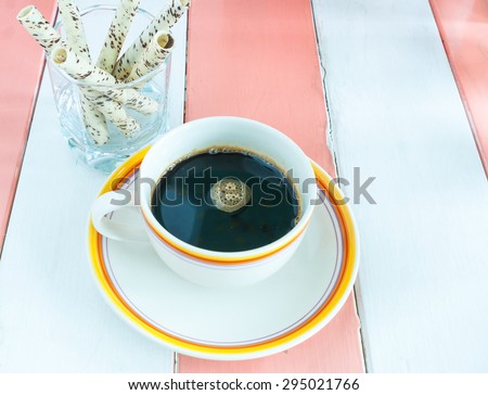 cup coffee and wafer stick on color wooden background