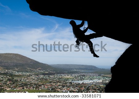 Rock climber climbing over a small town
