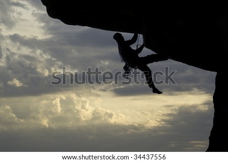 Rock climber climbing on overhang at sunset
