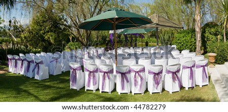 Prepared outdoor wedding ceremony with chairs and purple ribbons