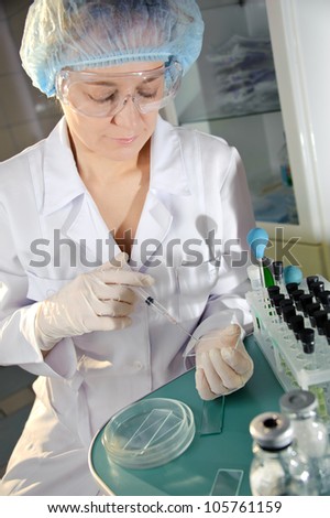 Female doctor in glasses examines a sample.  Could be useful for medicine, hospital, research and development, clinical studies, forensics, science etc