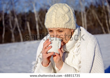 adult woman in white, with mug in his hands  on a snowy background, bright sunny frosty day