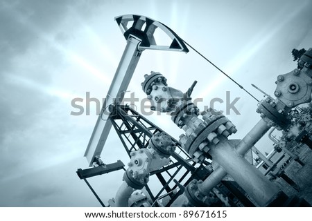 Extraction of oil. Pump jack and oil wellhead. Toned.