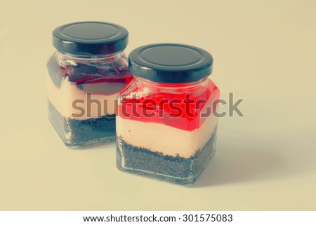 Two jars with creamy dessert: brownie base and yogurt topped with blueberries and Strawberry