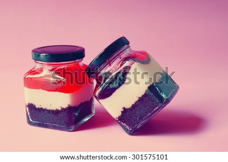 Two jars with creamy dessert: brownie base and yogurt topped with blueberries and Strawberry