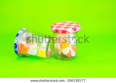 Colorful jelly candies in jar on green background
