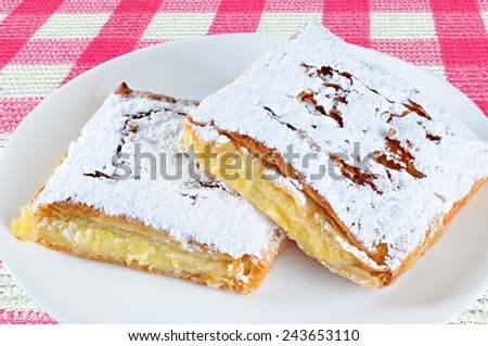 Two pieces of cheese pie with sugar on a plate, on a tablecloth