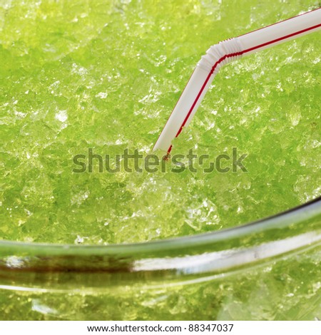 Closeup of a green drink with crushed ice with a straw in it.