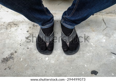 Close up man\'s lags in jeans with socks and slippers