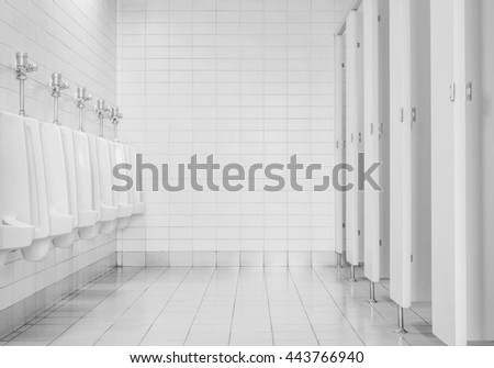 Closeup tiles wall in the toilet of man with toilet view by urinals and small room , interior at the old toilet background in black and white tone , interior of toilet in the office
