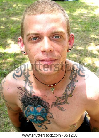 Young man heavily tattooed with pierced ears and nipples