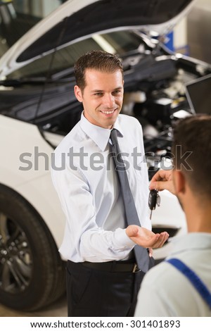 Auto mechanic giving his car key at customer.
