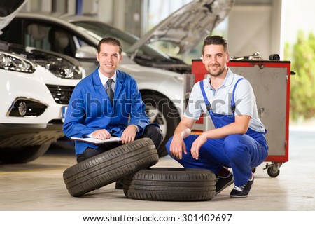 Auto mechanics posing at camera with tire.