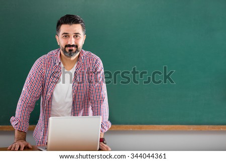 Young man teacher posing in classroom.