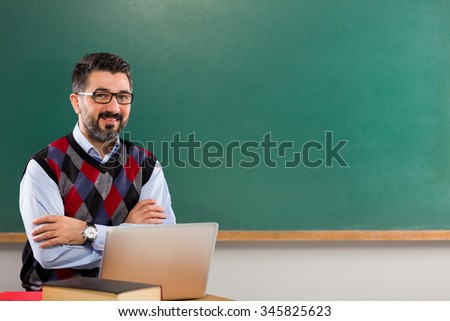 Young man teacher posing in classroom.