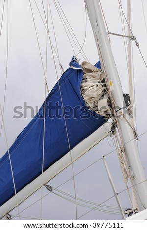 Yacht sail packed into a blue sleeve on boom.