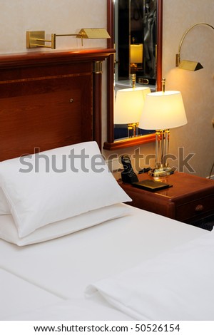 Bed and night table with note book, phone and lamp in a hotel room.