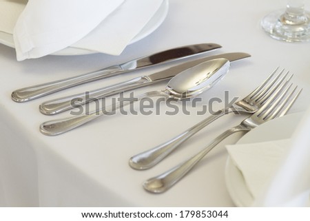 wedding or dinner table place setting - fork, knife and spoon in elegant setting
