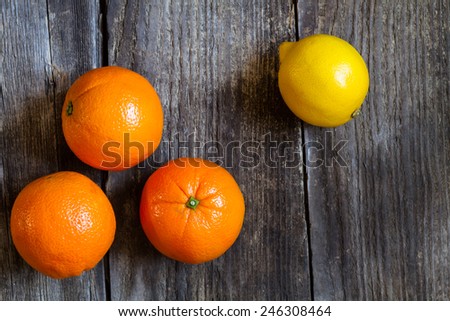 oranges and lemon on textured weathered wooden table - top view