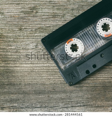 audio cassette with magnetic tape on wooden background - colorized photo